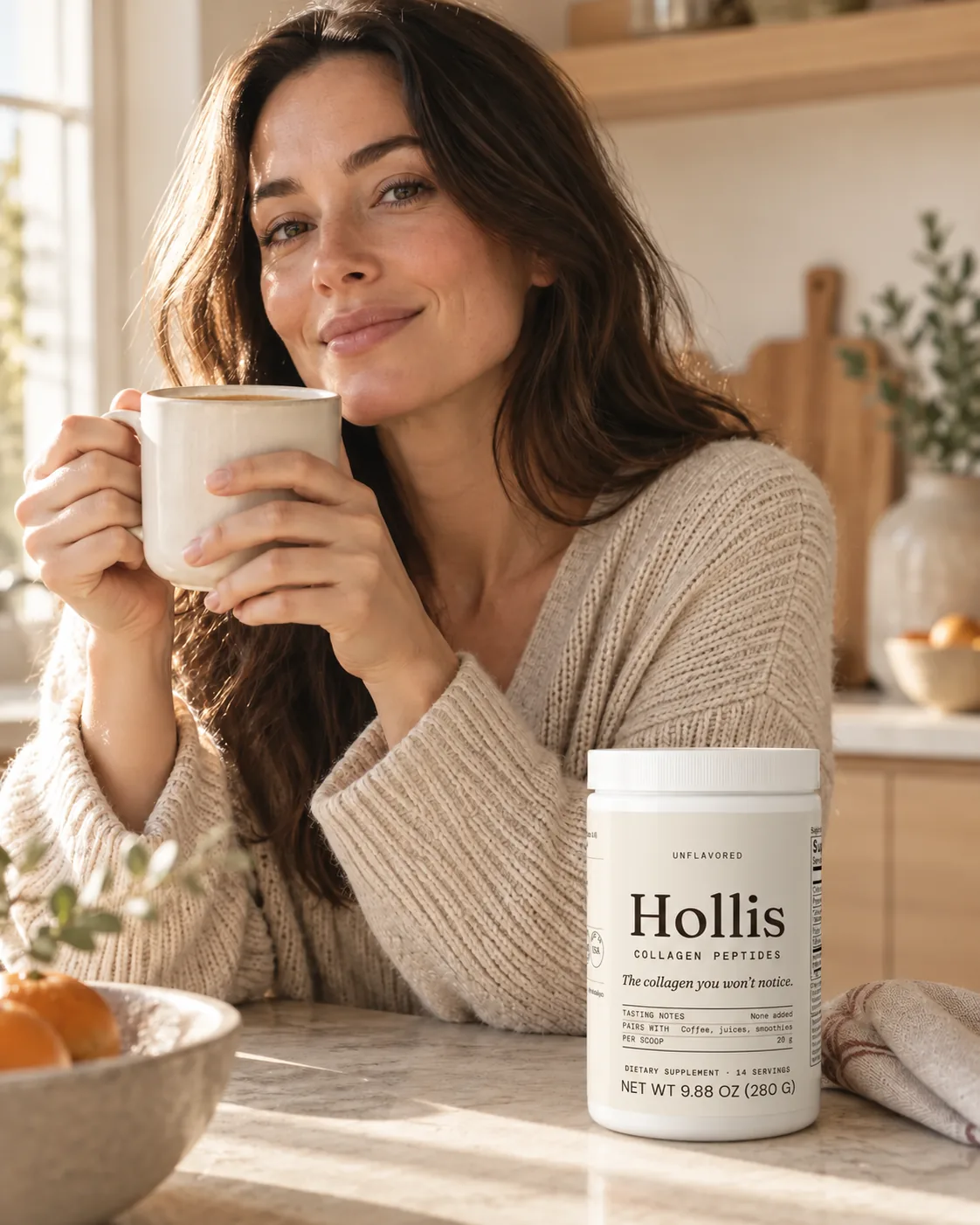 A woman holding a mug in a sunlit kitchen, the Hollis container on the counter